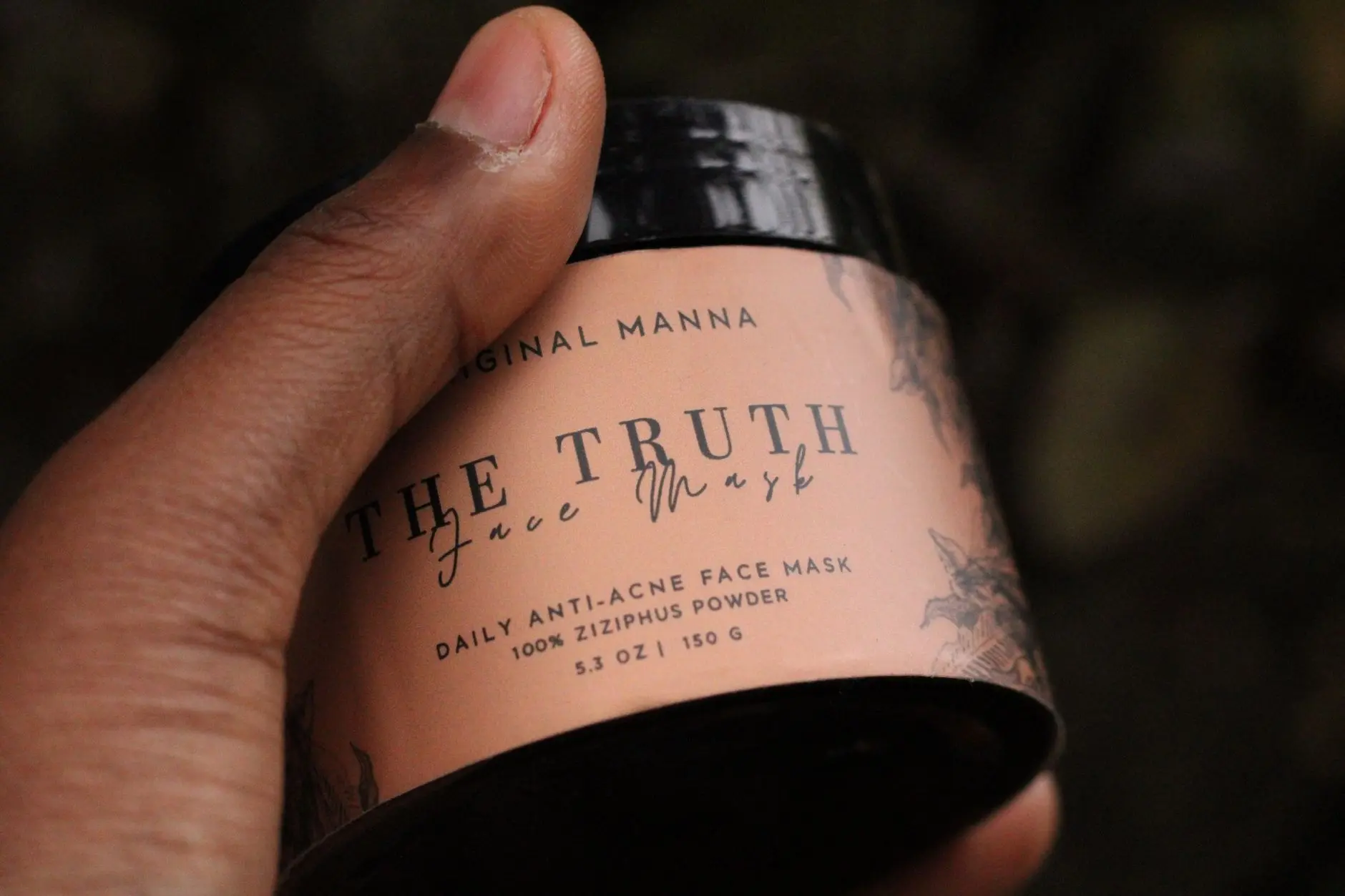 Primer plano de una mano sosteniendo la máscara facial diaria anti-acné 'The Truth' con polvo de Ziziphus.
