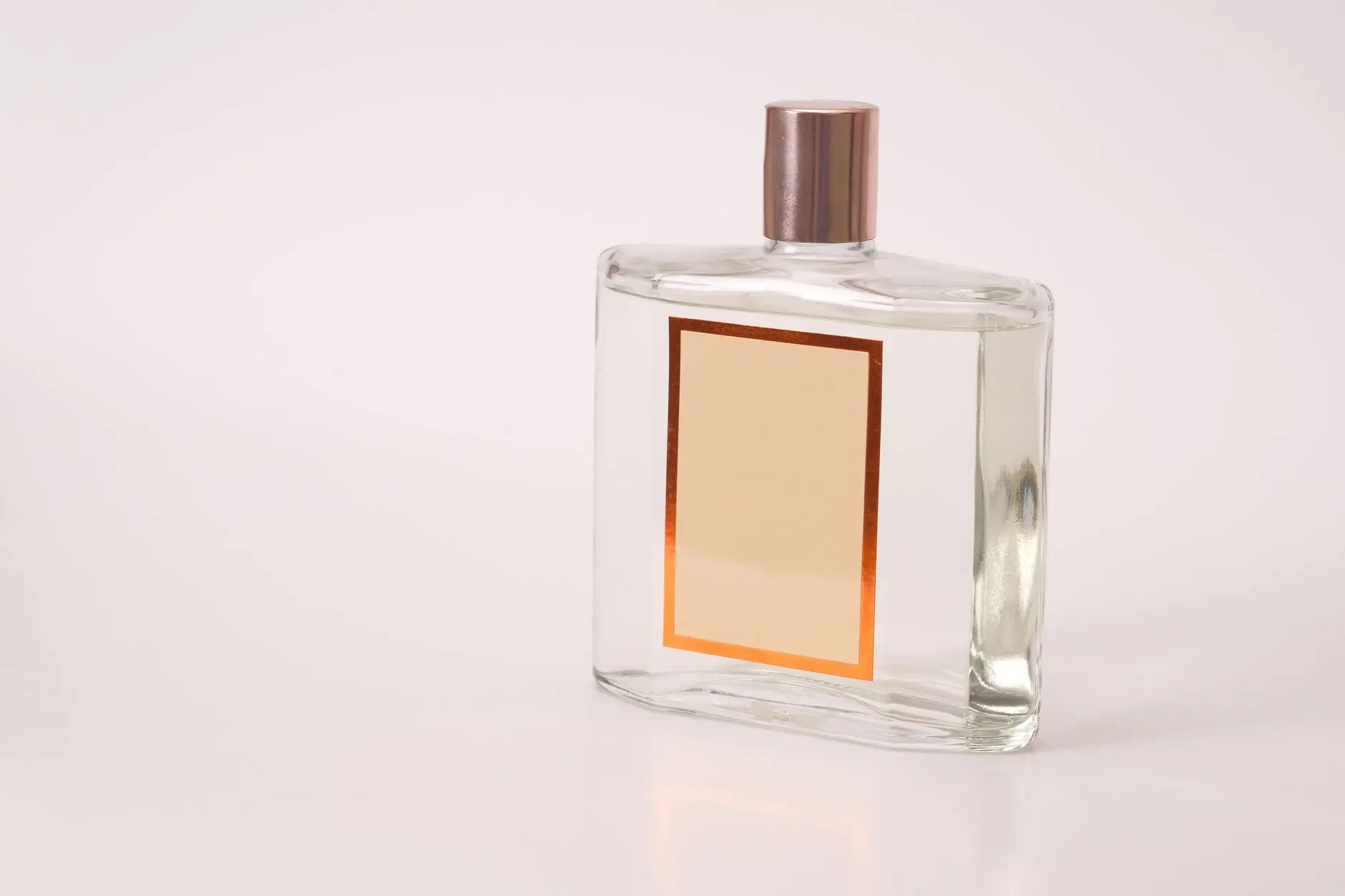 Un frasco de perfume transparente con etiqueta vacía, adecuado para branding o fines de diseño.