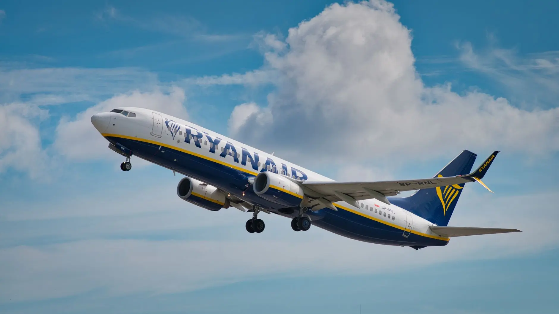 Un avión de Ryanair asciende hacia el cielo, mostrando detalles del tren de aterrizaje y las alas.