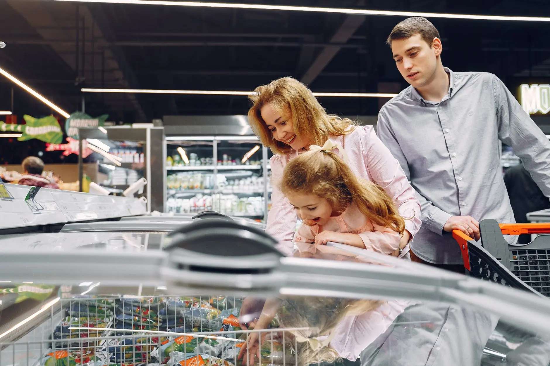 Una familia disfrutando del tiempo juntos mientras compra en un pasillo del supermercado.