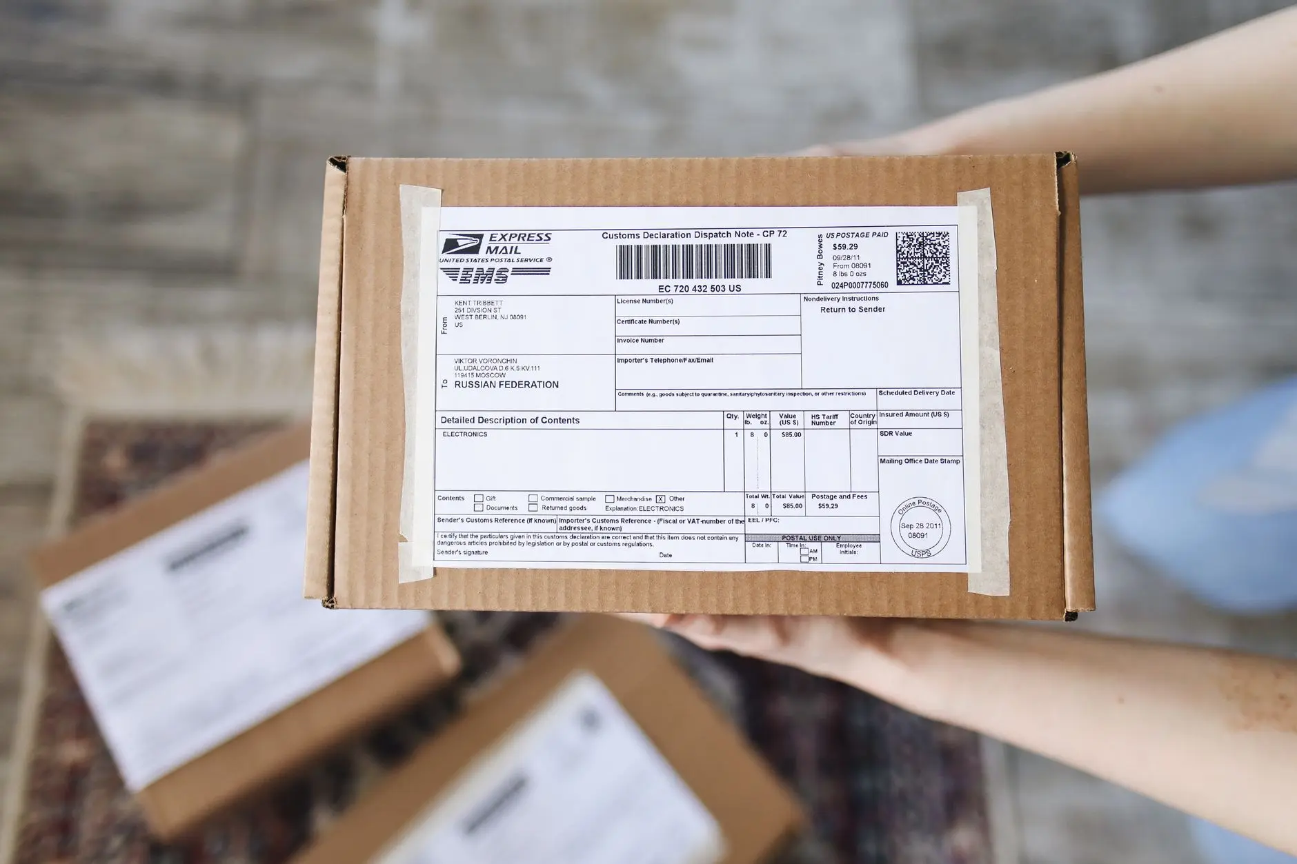 Vista superior de manos sosteniendo un paquete de correo exprés con declaración de aduana.