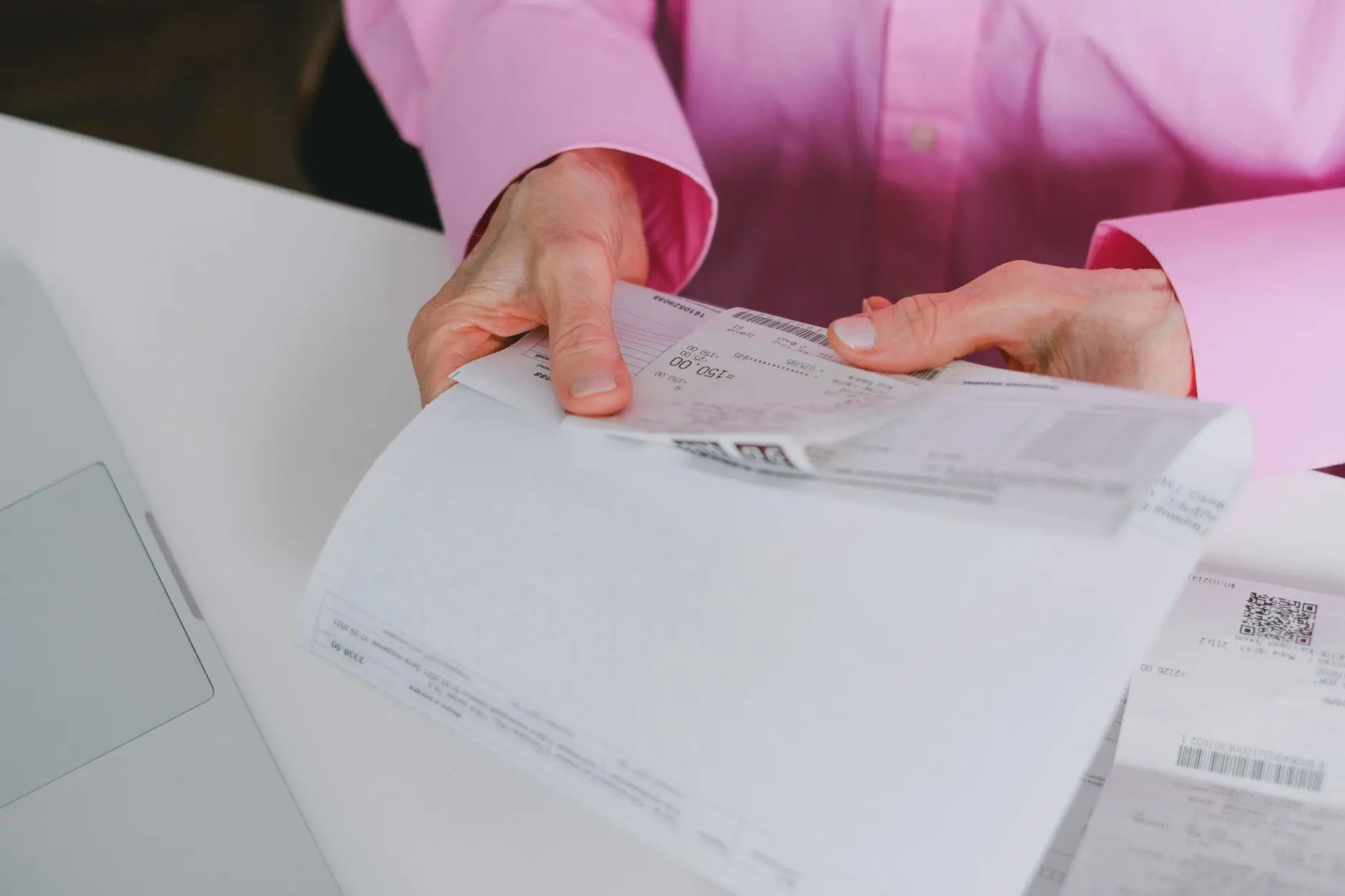Persona de negocios manejando recibos en papel, meticulosamente organizados.