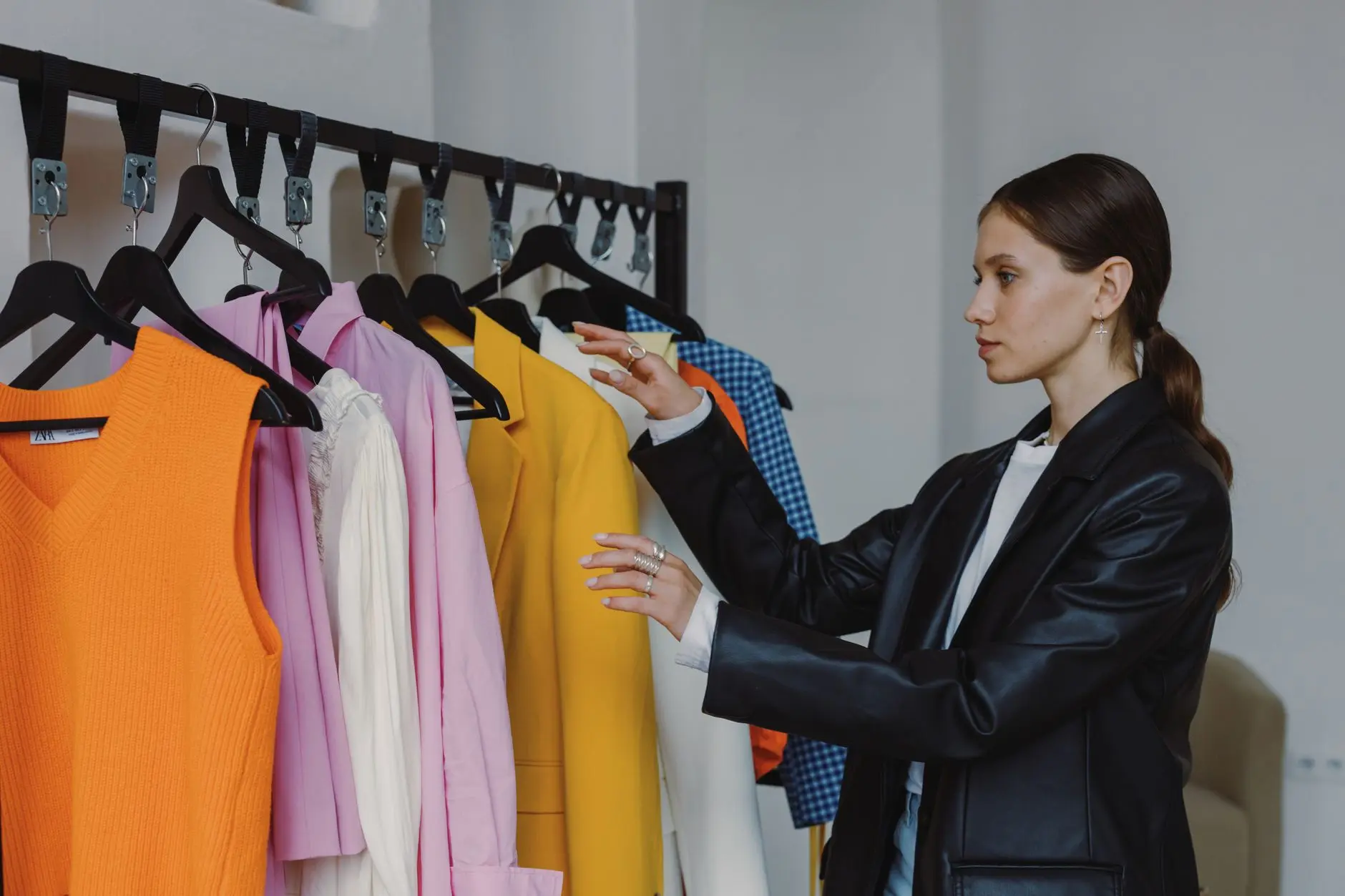 Vista lateral de una mujer navegando por una colorida colección de moda en una tienda moderna.
