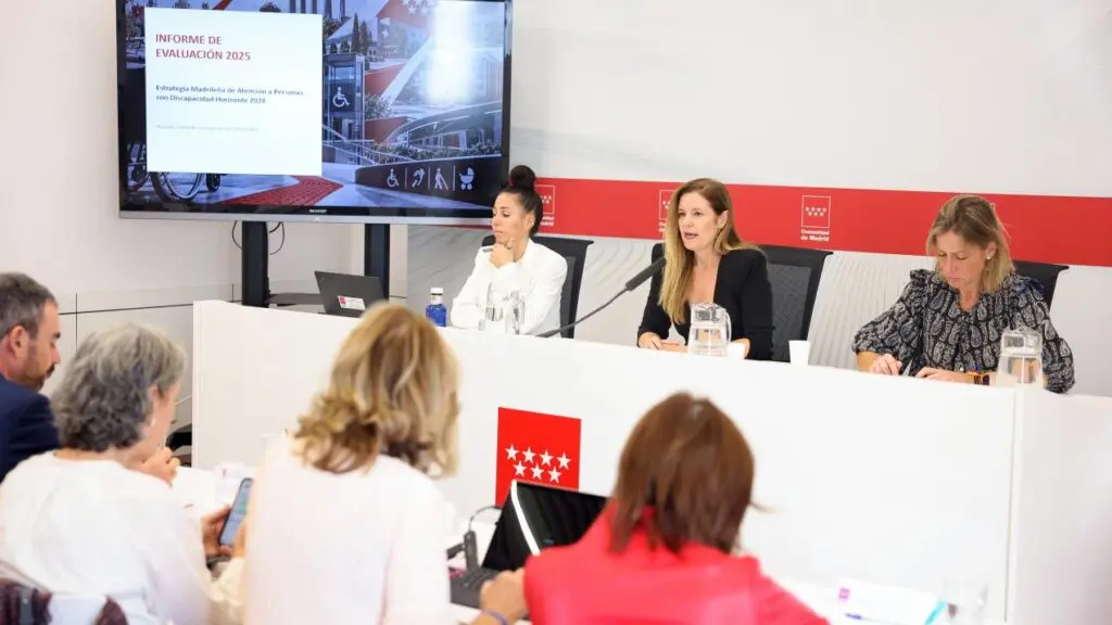Mujeres participan en una reunión mientras una pantalla muestra un informe sobre discapacidad.