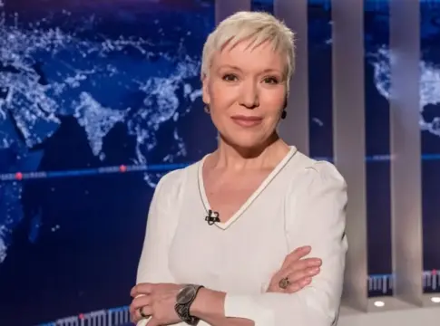 Rosa María Molló en un estudio de televisión Rosa María Molló posa con los brazos cruzados ante un mapa mundial.