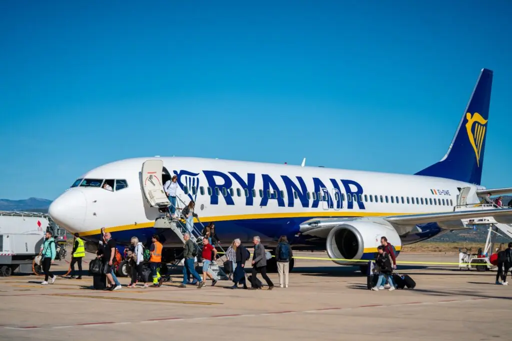 Avión de Ryanair en la pista mientras varios pasajeros suben por la escalerilla.
