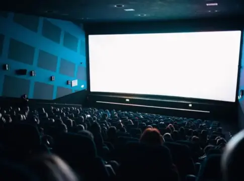 Espectadores en una sala de cine Sala de cine llena de espectadores frente a una gran pantalla iluminada.