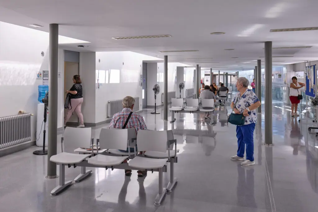 Sala de espera de un centro sanitario Sala de espera de un centro sanitario con varias personas sentadas y de pie.