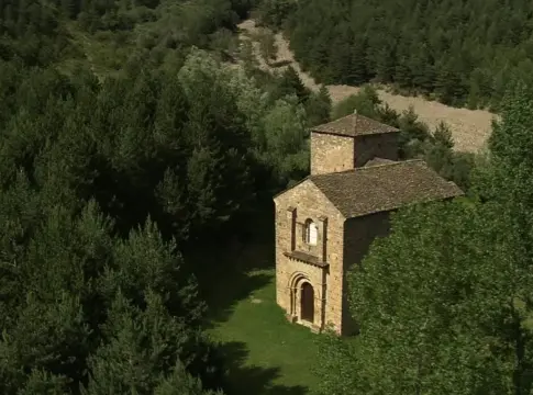 Iglesia de piedra entre el bosque Iglesia románica de piedra rodeada de bosque, vista desde una perspectiva elevada.