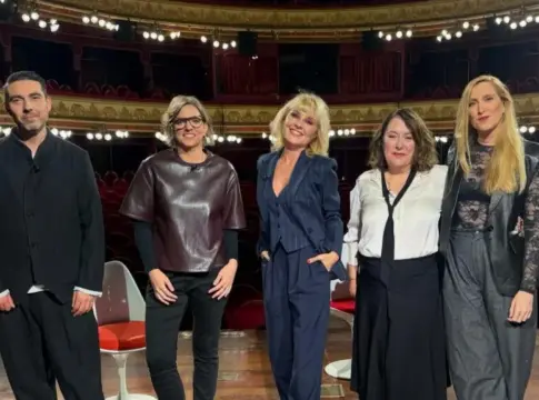 Grupo posa en un teatro Seis personas posan frente a las butacas rojas de un teatro ornamentado.