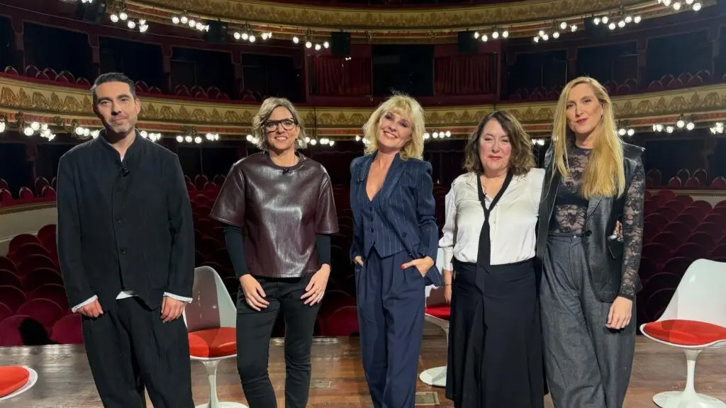 Grupo posa en un teatro Seis personas posan frente a las butacas rojas de un teatro ornamentado.