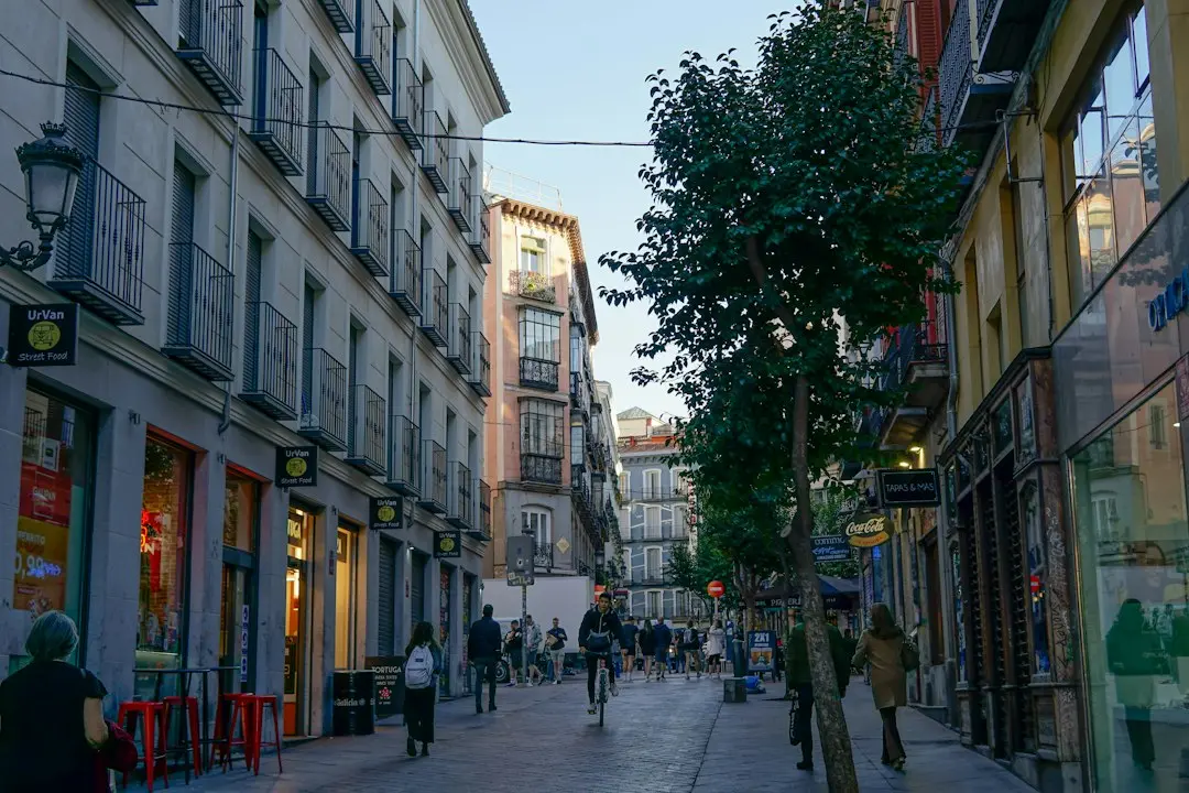 a group of people walking down a street next to tall buildings