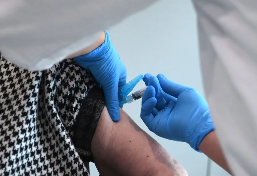 Una persona recibe una inyección en el brazo de manos enguantadas.