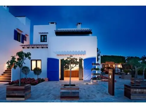 Villa blanca con puertas azules al anochecer Villa blanca de varios niveles con puertas azules y patio ajardinado al anochecer