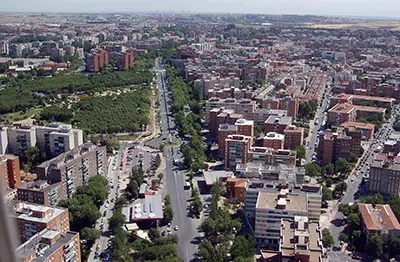Vista aérea de una ciudad con edificios residenciales, zonas verdes y una avenida central.